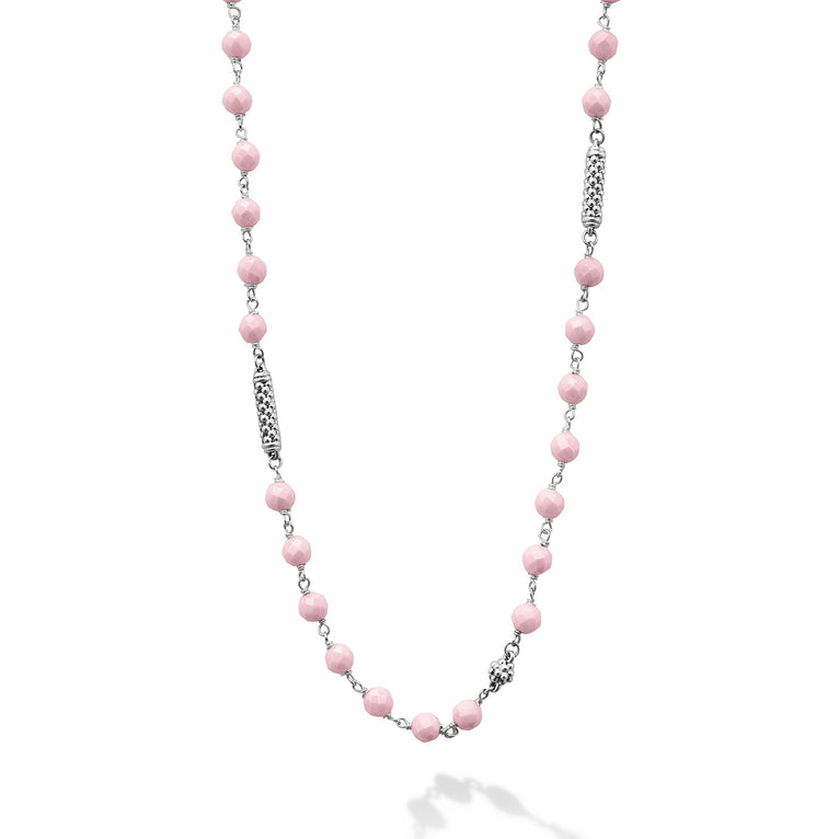 A close-up of a sterling silver and ceramic beaded necklace in the middle of a white background featuring pink ceramic and silver Caviar beading.