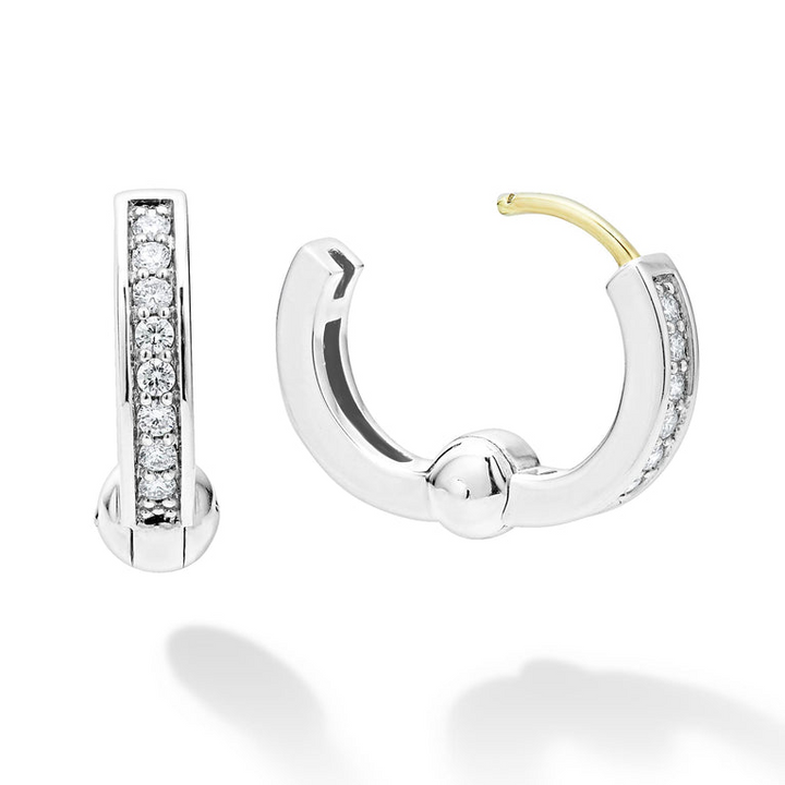 A pair of huggie earrings with diamonds set in a smooth sterling silver circle motif. The right earring is angled to the side, unclasped.