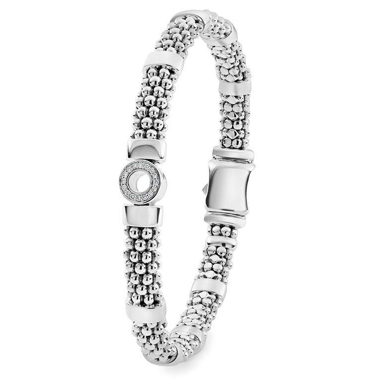 A sterling silver bracelet standing vertically in the middle of a white background featuring one diamond circle station and caviar beading.