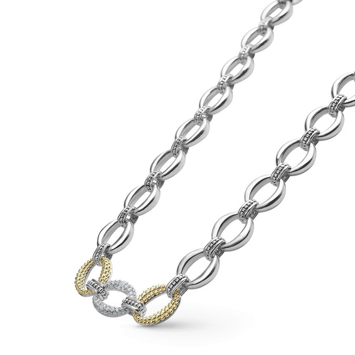 A close-up of a sterling silver &18k gold necklace angled to the right, featuring a pave diamond link, caviar beading, and a lobster clasp against a white background.