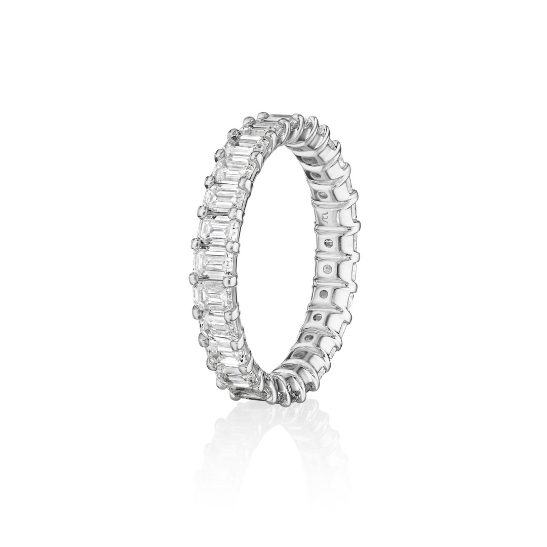 Close-up photo side-view tilted to the left of a white gold women's wedding band with emerald cut diamonds on a white background