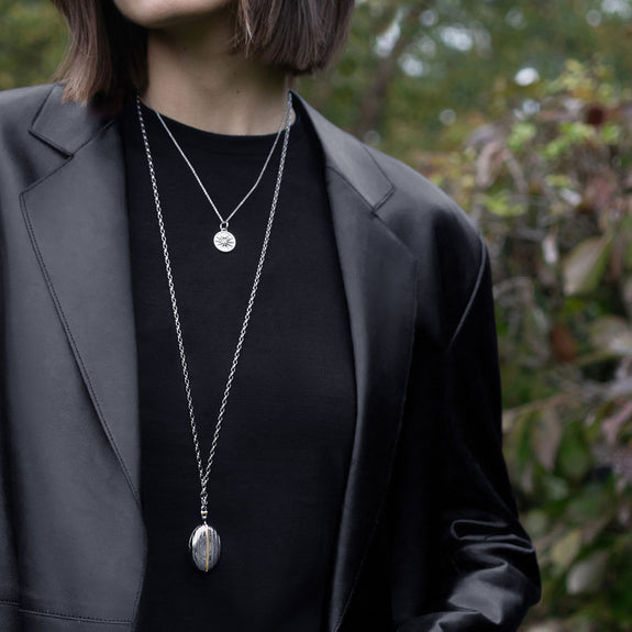 A man is wearing a two-tone Pinstripe Locket with a black sports coat.