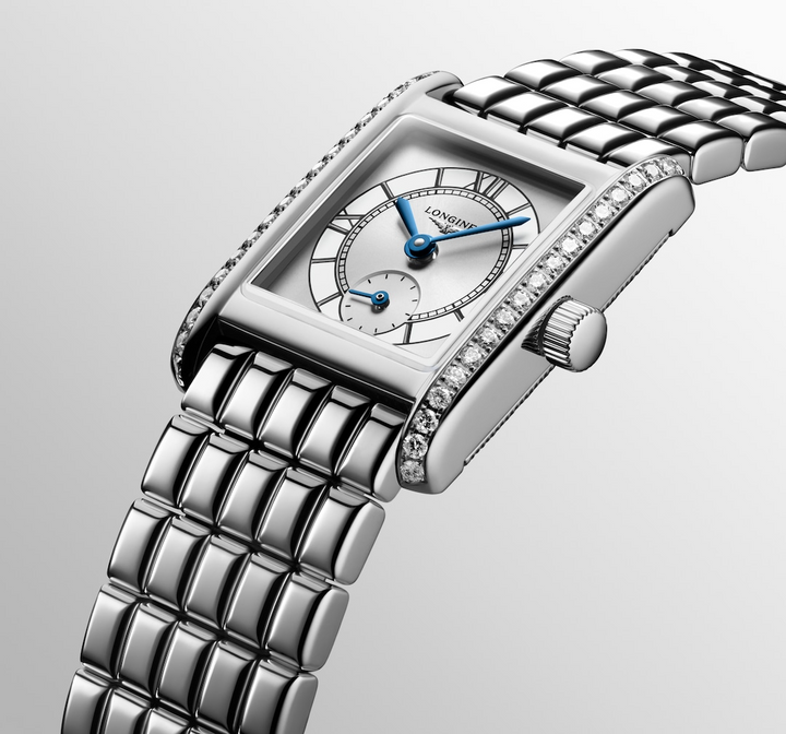 A Longines watch is displayed in the middle, angled to the right on a white background. The rectangular-shaped watch features a white dial, blue hands, black markers, a stainless steel diamond-set bezel, and a stainless steel bracelet.