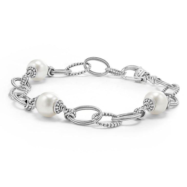 A Sterling Silver link bracelet rests in the middle of a white background. It has three cultured freshwater pearl stations and caviar-beaded links.