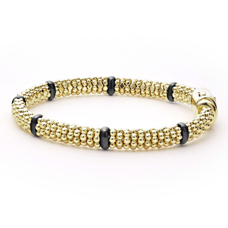 An 18k gold bracelet resting in the middle of a white background. The bracelet features smooth black stations and caviar beading.