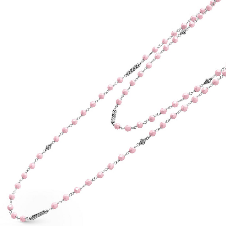 A sterling silver and ceramic beaded necklace angled to the right in the middle of a white background featuring Pink ceramic and silver Caviar beading.