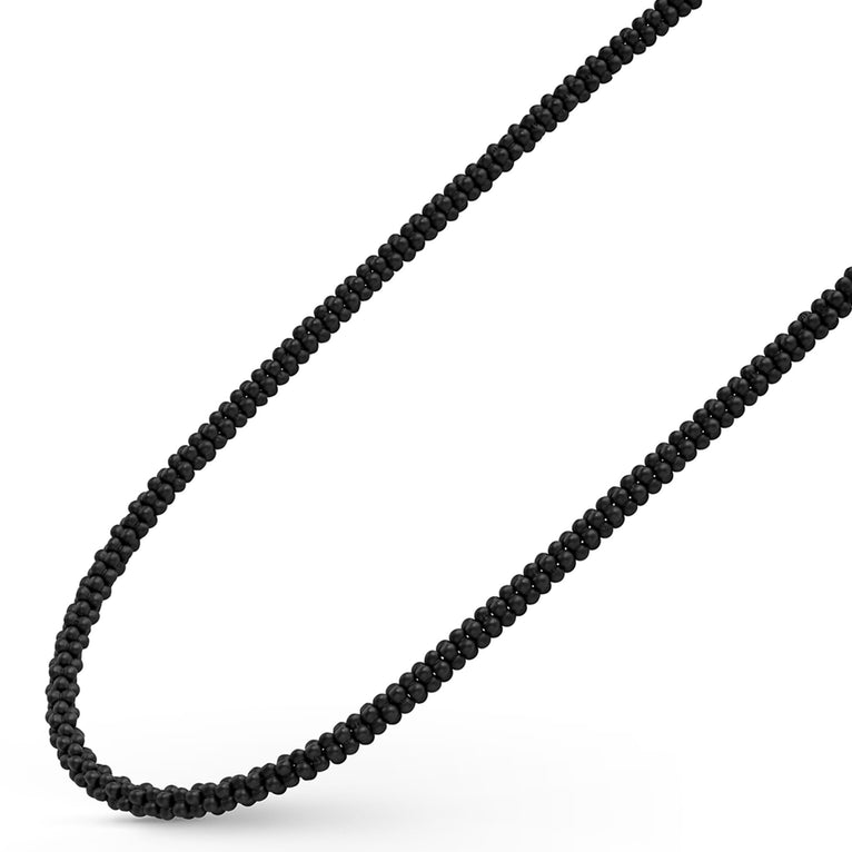 A sterling silver and ceramic beaded necklace angled to the right in the middle of a white background featuring matte black ceramic caviar beading.