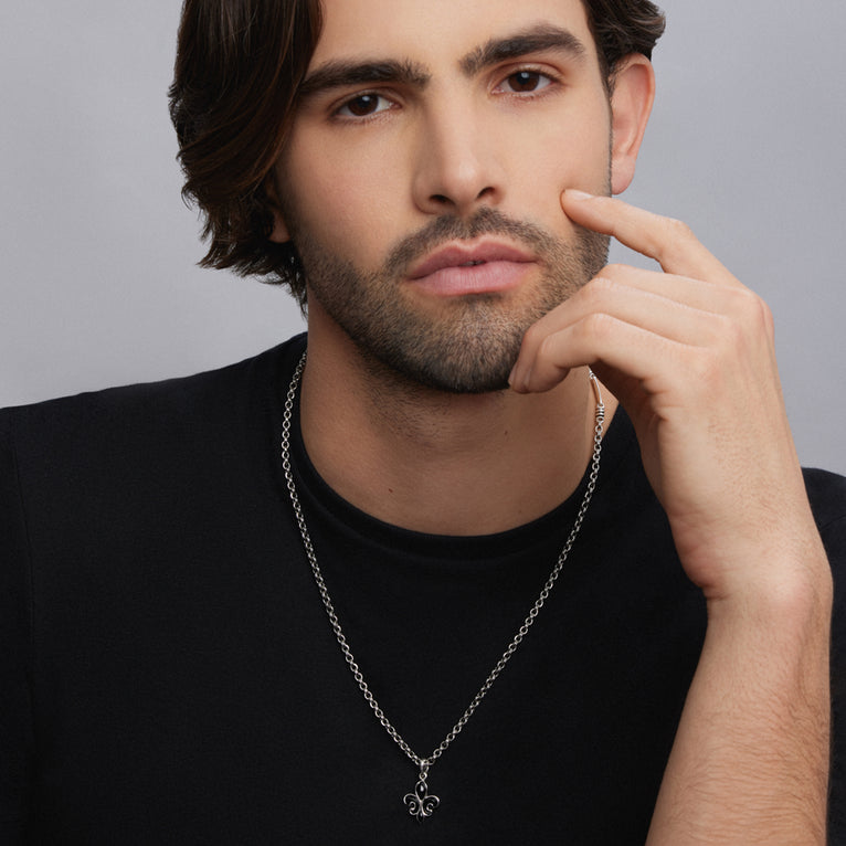 A man is wearing a Black Agate Fleur De Lis Amulet with a chain necklace