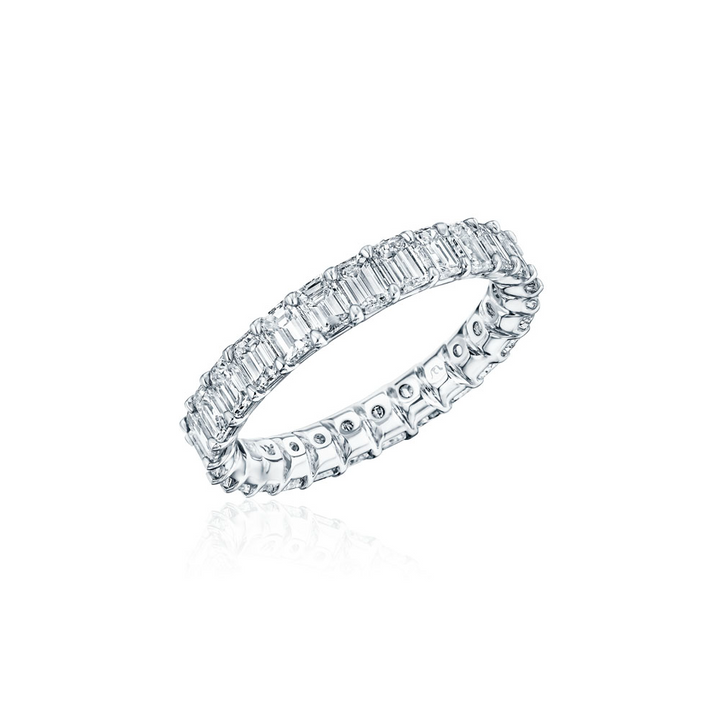 Close-up photo of a white gold women's wedding band angled to the right with emerald cut diamonds on a white background