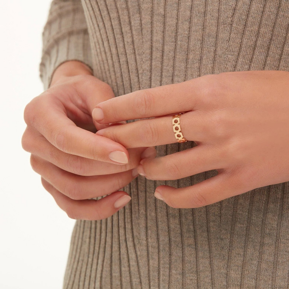 A close-up of a woman wearing a yellow gold ring with a unique spaced yellow-gold ring.