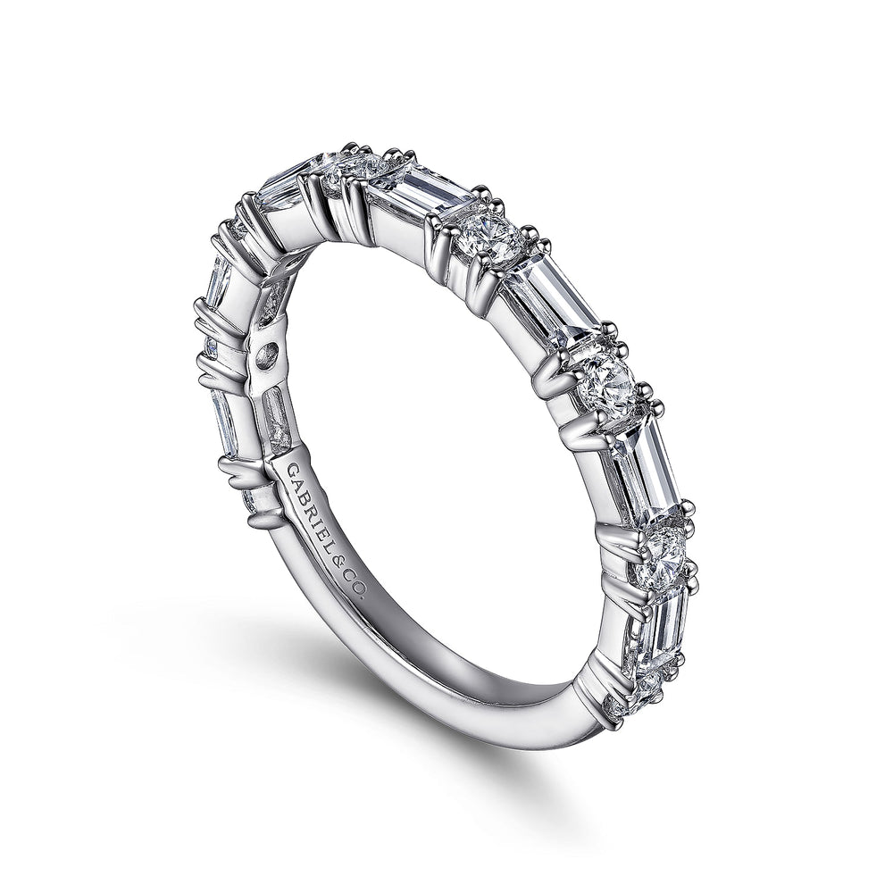 A white gold ring angled right in the middle of a white background. The ring features alternating prong-set baguette and round diamonds in a 3/4 eternity style.
