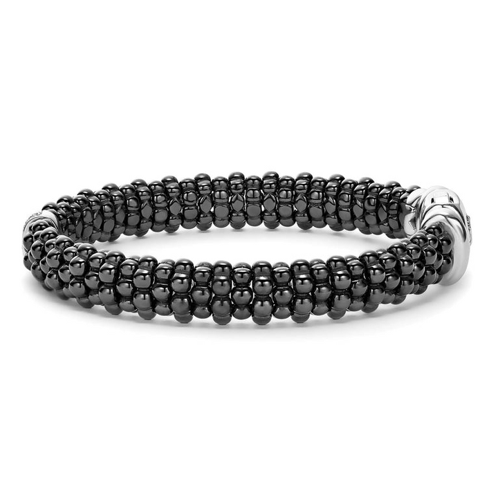 A side-view of a sterling silver bracelet in the middle of a white background featuring diamonds is set in silver and surrounded by black ceramic Caviar beading.