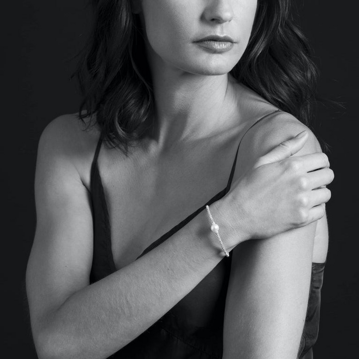 A woman wearing a Sterling silver and 18k gold bracelet featuring a cultured freshwater pearl station with Caviar beading in 18K gold and sterling silver