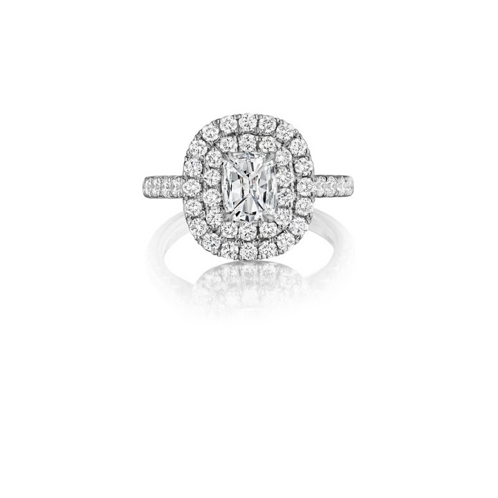 The Double Halo Engagement Ring, made of white gold, lies flat against a white background. It features a brilliant-cut diamond set in the center, a double halo, and a round diamond-set band.