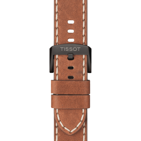 A close-up of a Tissot watch with a leather strap with an engraved buckle. 