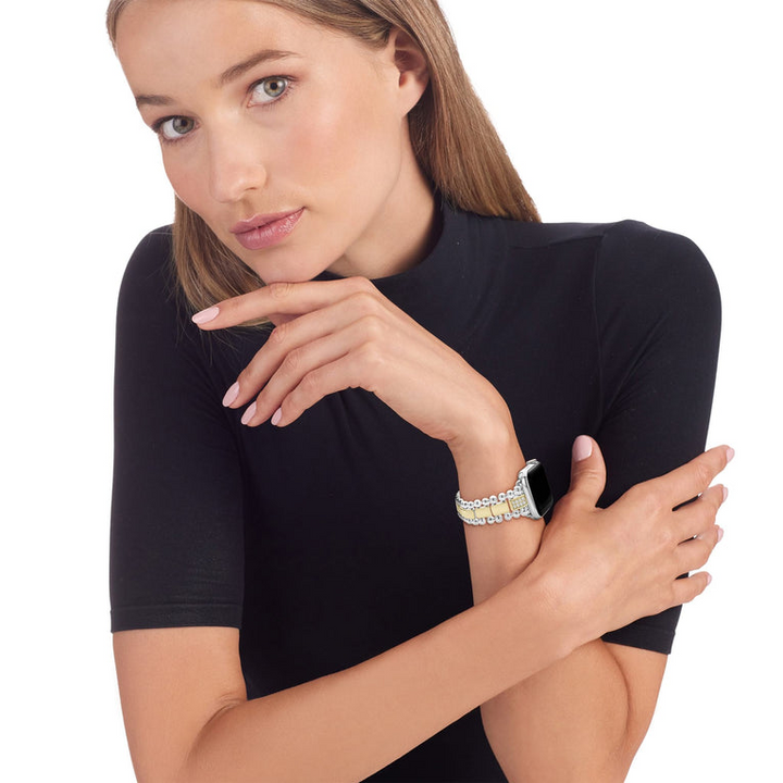 A woman wearing a black turtleneck and an Apple Watch around her wrist. The watch band features 18K gold-stationed links and stainless steel beading around the links.