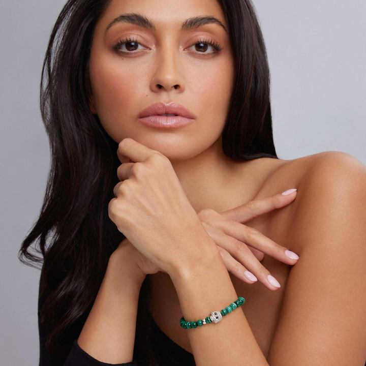 A woman is wearing a sterling silver bracelet featuring a Malachite gemstone beaded bracelet with a silver Caviar skull.