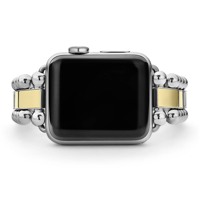 An Apple watch rests in the middle horizontally against a white background, showcasing the Apple watch face. The watch band features 18K gold-stationed links and stainless steel beading around the links.