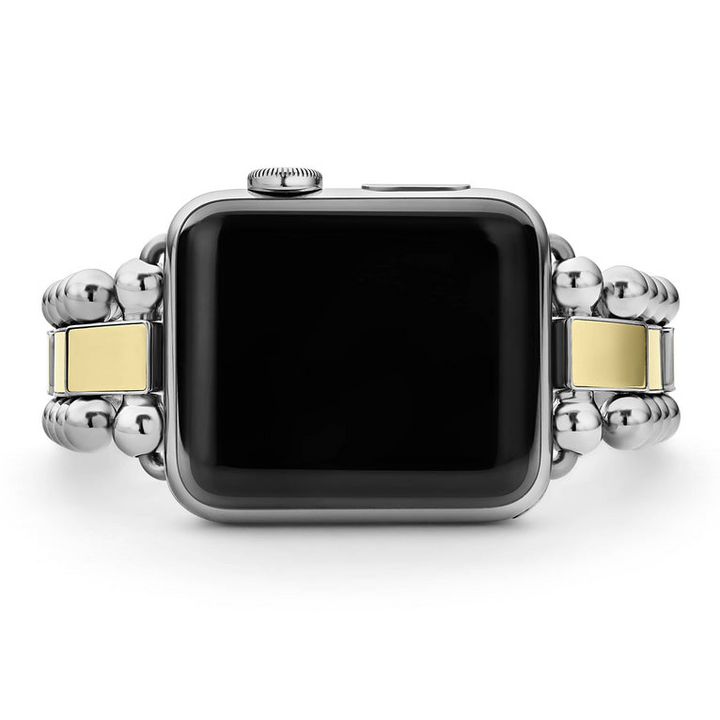 An Apple watch rests in the middle horizontally against a white background, showcasing the Apple watch face. The watch band features 18K gold-stationed links and stainless steel beading around the links.