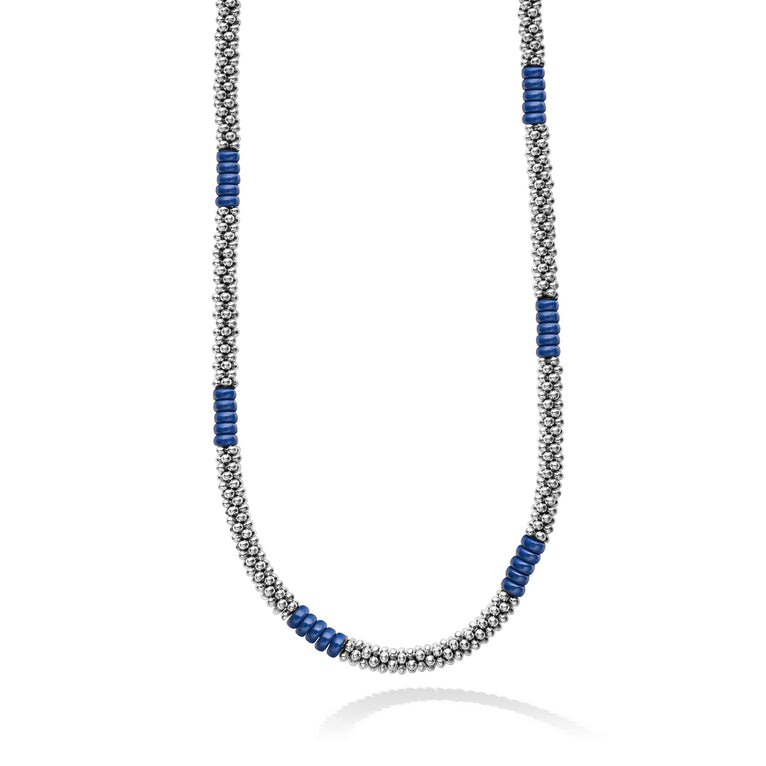 A close-up of a sterling silver and ceramic beaded necklace in the middle of a white background featuring blue ceramic and silver Caviar beading.