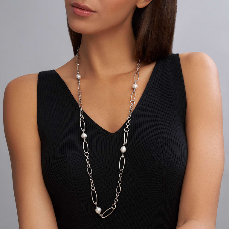 A woman is wearing a sterling silver necklace featuring five cultured freshwater pearl stations and Caviar beading displayed on a white background.