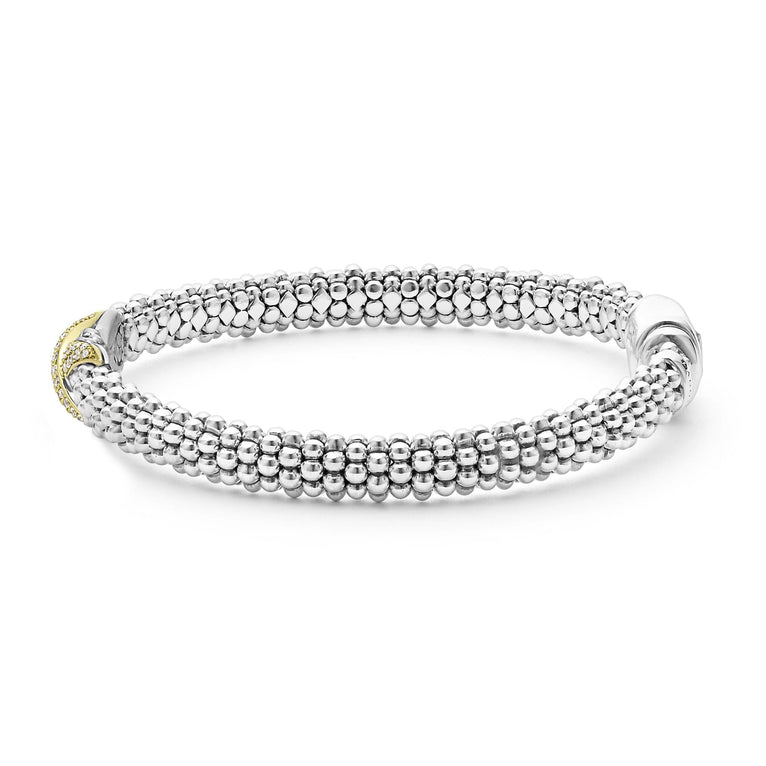 A side-view of a Sterling Silver & 18k gold bracelet in the middle of a white background. The bracelet features a diamond-set X station, caviar beading, and a stainless steel clasp.