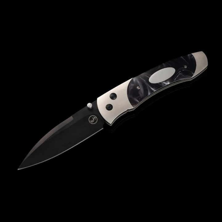 A close-up of a pocket knife with the blade out. The pocket knife features an aerospace-grade titanium frame, inlays of compressed acrylic resin with an inset engraving plate, and a three-layer billet blade.