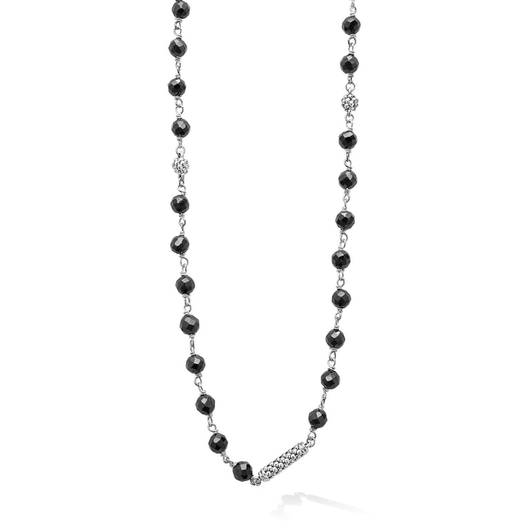 A close-up of a sterling silver and ceramic beaded necklace in the middle of a white background featuring black ceramic and silver Caviar beading.