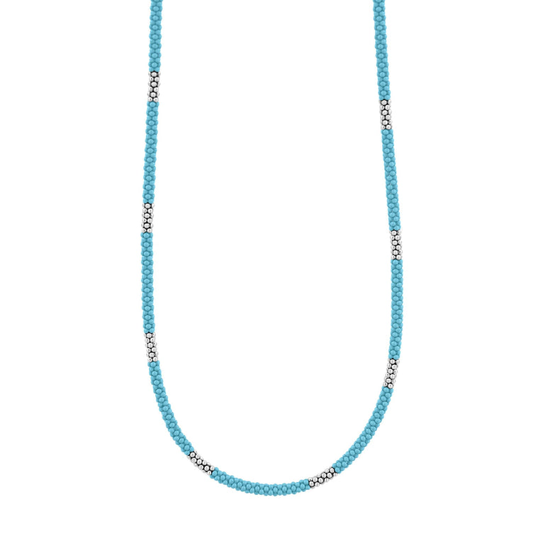 A close-up of a sterling silver and ceramic beaded necklace in the middle of a white background featuring light blue ceramic and silver Caviar beading.