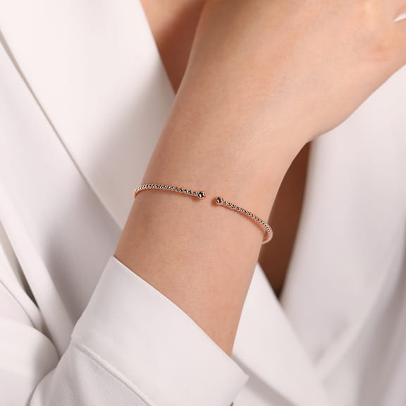Model wearing the Gabriel & Co Bujukan rose gold split bangle with a white blouse