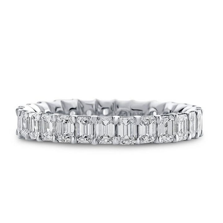 Close-up photo of a white gold women's wedding band with emerald cut diamonds on a white background