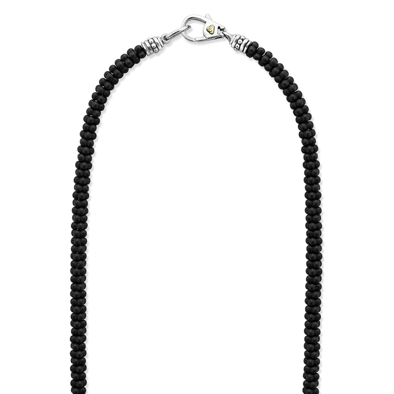 A sterling silver and ceramic beaded necklace in the middle of a white background featuring matte black ceramic caviar beading.