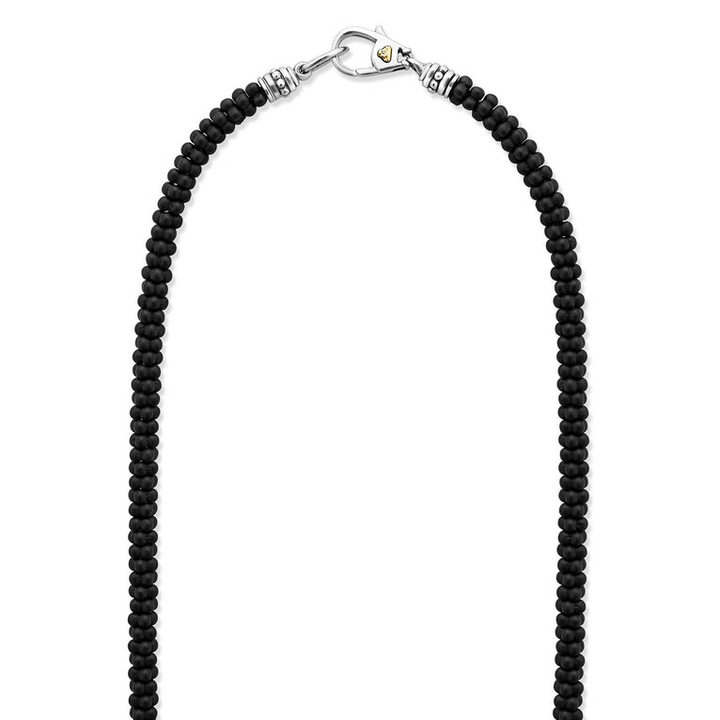 A sterling silver and ceramic beaded necklace in the middle of a white background featuring matte black ceramic caviar beading.