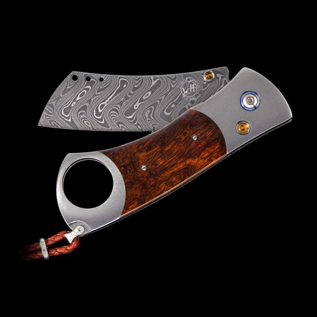 A close-up of a pocket knife with the blade halfway angled to the left. The pocket knife features a titanium Cigar Cutter with a Desert Ironwood handle and a Damascus steel blade.