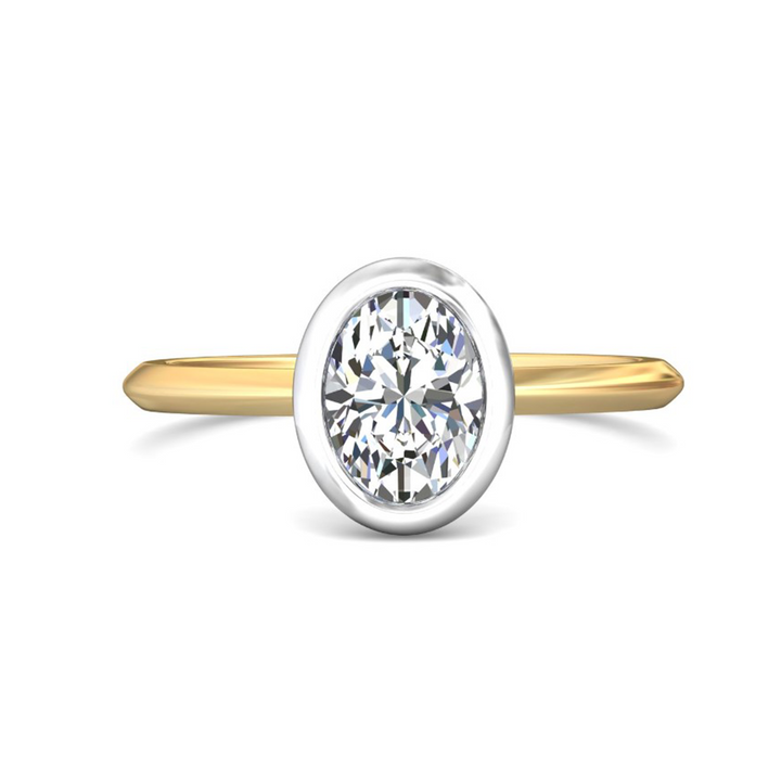 The Bezel Set Engagement Ring, made of yellow gold, lies flat against a white background. It features an oval-cut diamond set in the center with a white gold bezel setting.