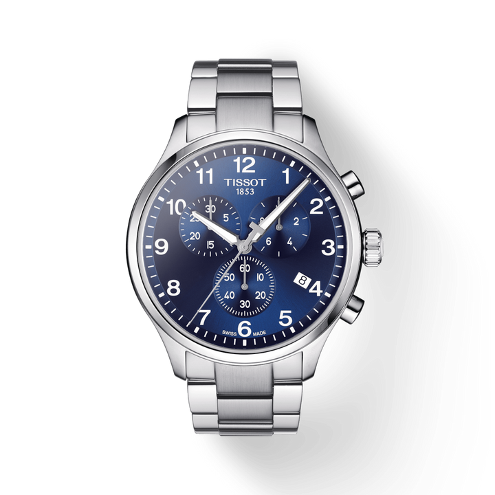 A Tissot watch laid out against a transparent background. The watch features a blue dial, white hands and markers, and a stainless steel bracelet.