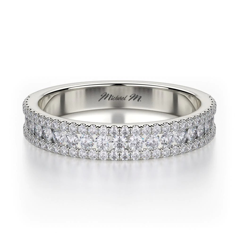 A white gold ring lies flat against a white background. It features a diamond set band with brilliant round-cut diamonds, and the "Michael M" inscription is visible inside it.