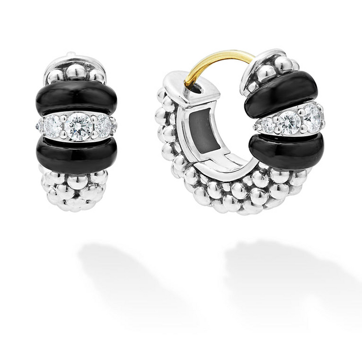 A pair of huggie earrings with smooth black ceramic and diamonds with Caviar beading. The right earring is angled to the side. 