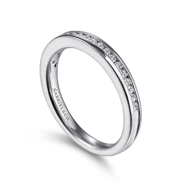 An angled view of a white gold wedding band against a white background. The ring features a half eternity style with channel-set round diamonds.