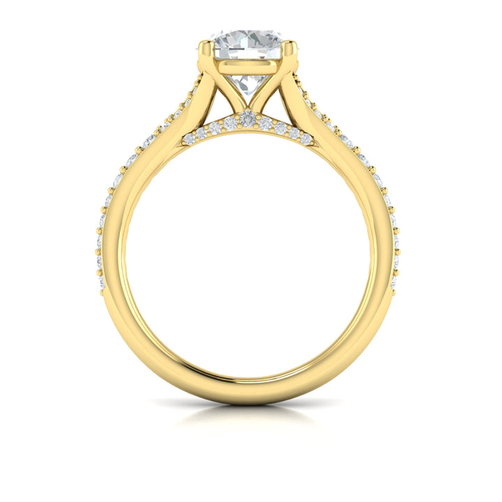 A top view of a yellow gold engagement ring is set against a white background. The engagement ring features a round center diamond, a split shank design, and a diamond-set band.