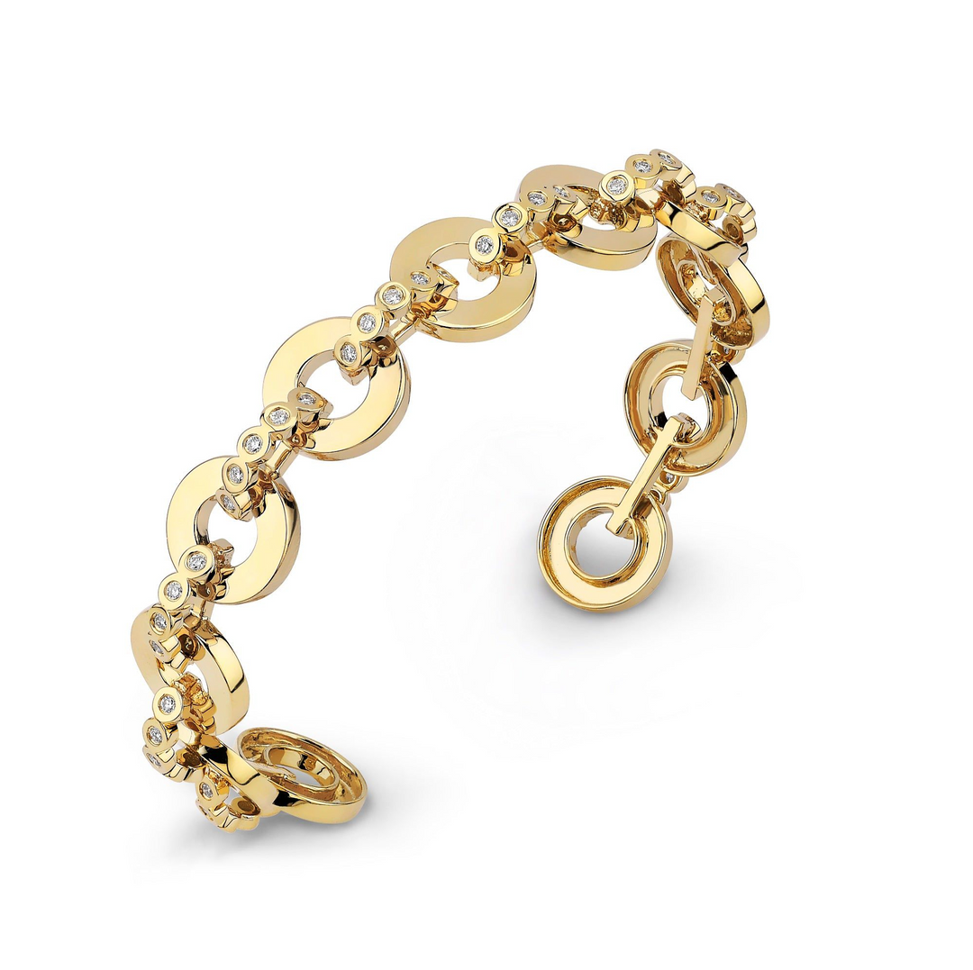 An angled view of a yellow gold bracelet cuff on a white background. The bracelet cuff features bezel-set stones that form arches connecting rings.