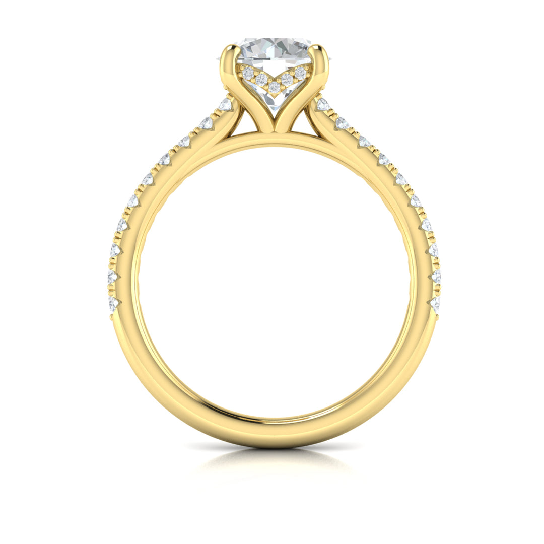 A top view of a yellow gold engagement ring is set against a white background. The engagement ring features a round center diamond, a hidden halo, and a diamond-set band.