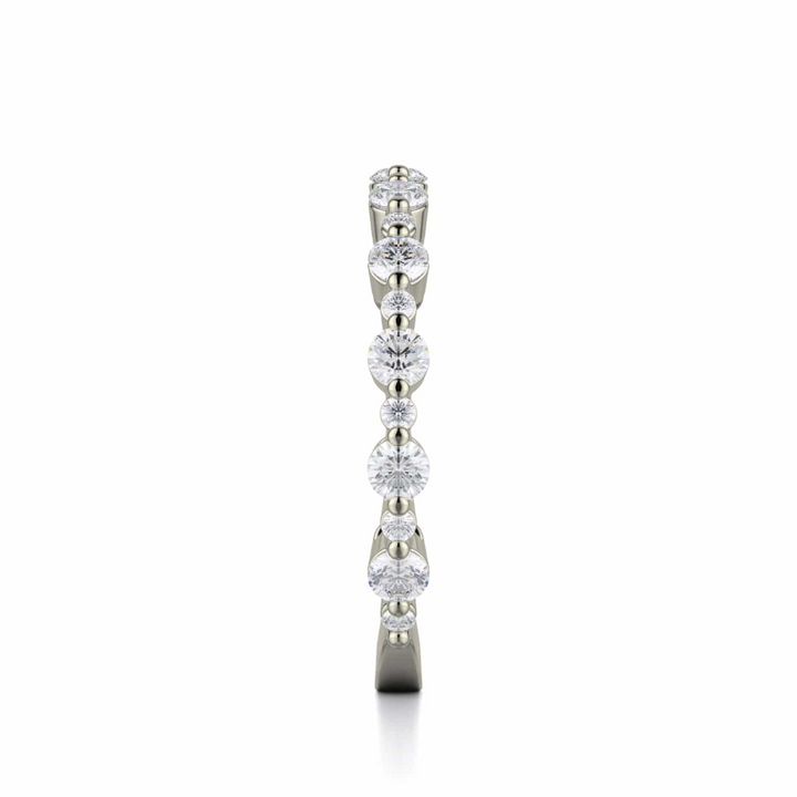 A side profile view of a white gold wedding band against a white background. The ring features a 3/4 eternity style with alternating sizes of prong-set round-shaped diamonds.