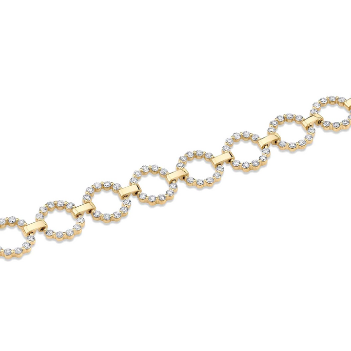 A top view of a diamond bracelet laid across a white background. The ring features a diamond ring with yellow gold signature shared prongs.