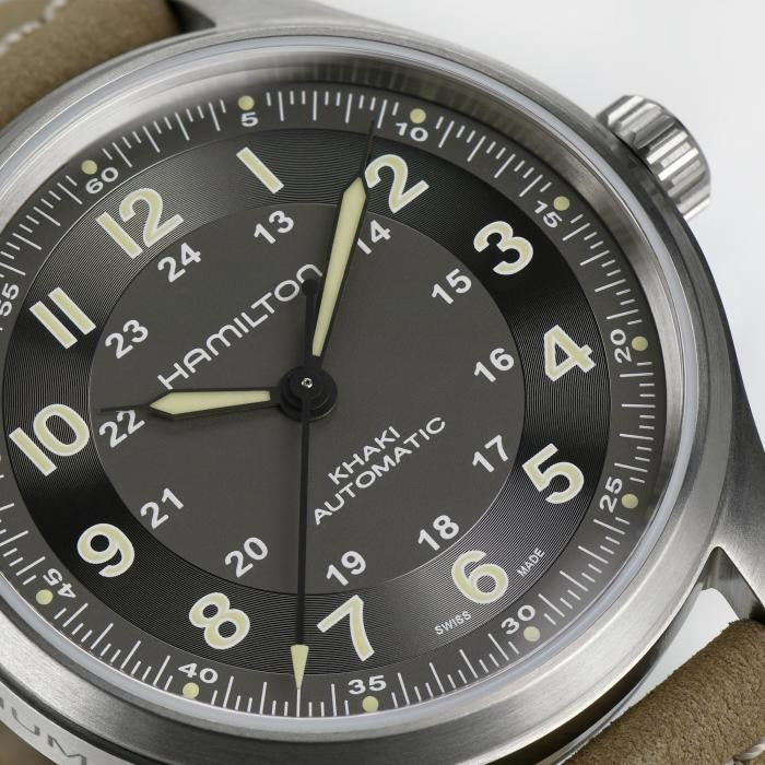 A close-up of a Hamilton watch, focusing on the dial, stainless steel case, and crown.