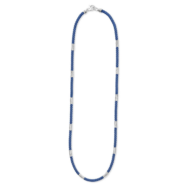 A sterling silver and ceramic beaded necklace in the middle of a white background featuring blue ceramic and silver Caviar beading.