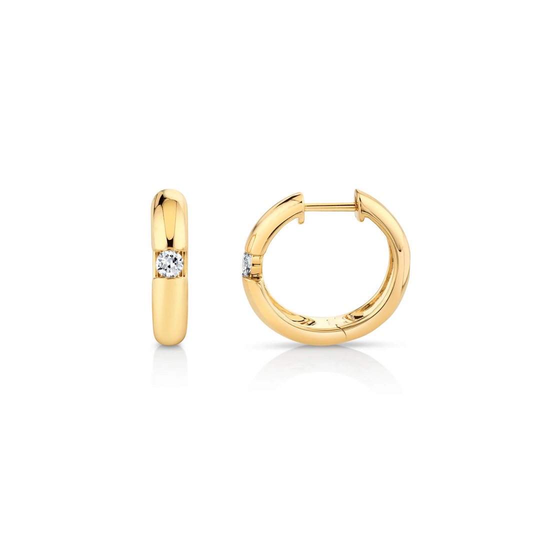 Two yellow-gold earrings lying flat across a white background. The rounded hoop earrings feature a floating diamond in the center.