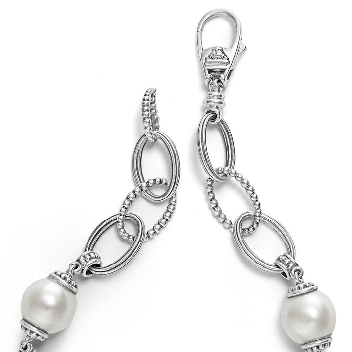 A Sterling Silver link bracelet rests in the middle of a white background. It has three cultured freshwater pearl stations and caviar-beaded links.