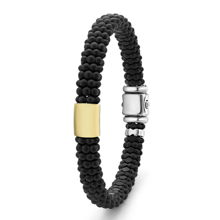 A sterling silver beaded bracelet standing vertically in the middle of a white background, featuring Matte black ceramic caviar beading and a gold single station