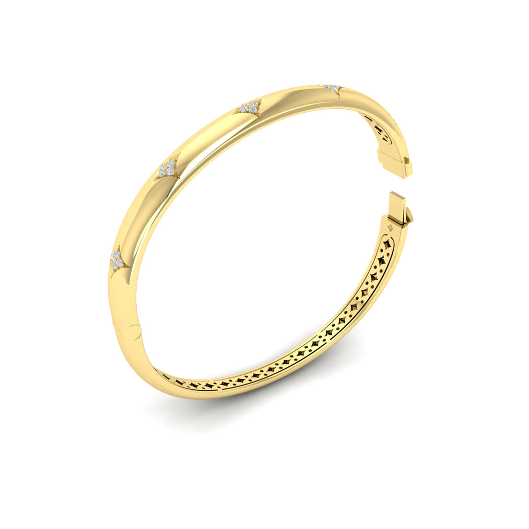 An angled view of a yellow-gold bracelet is set against a white background, showing the inside of the bracelet. The bracelet features a diamond-set star design across the yellow gold bangle with the clasp open.